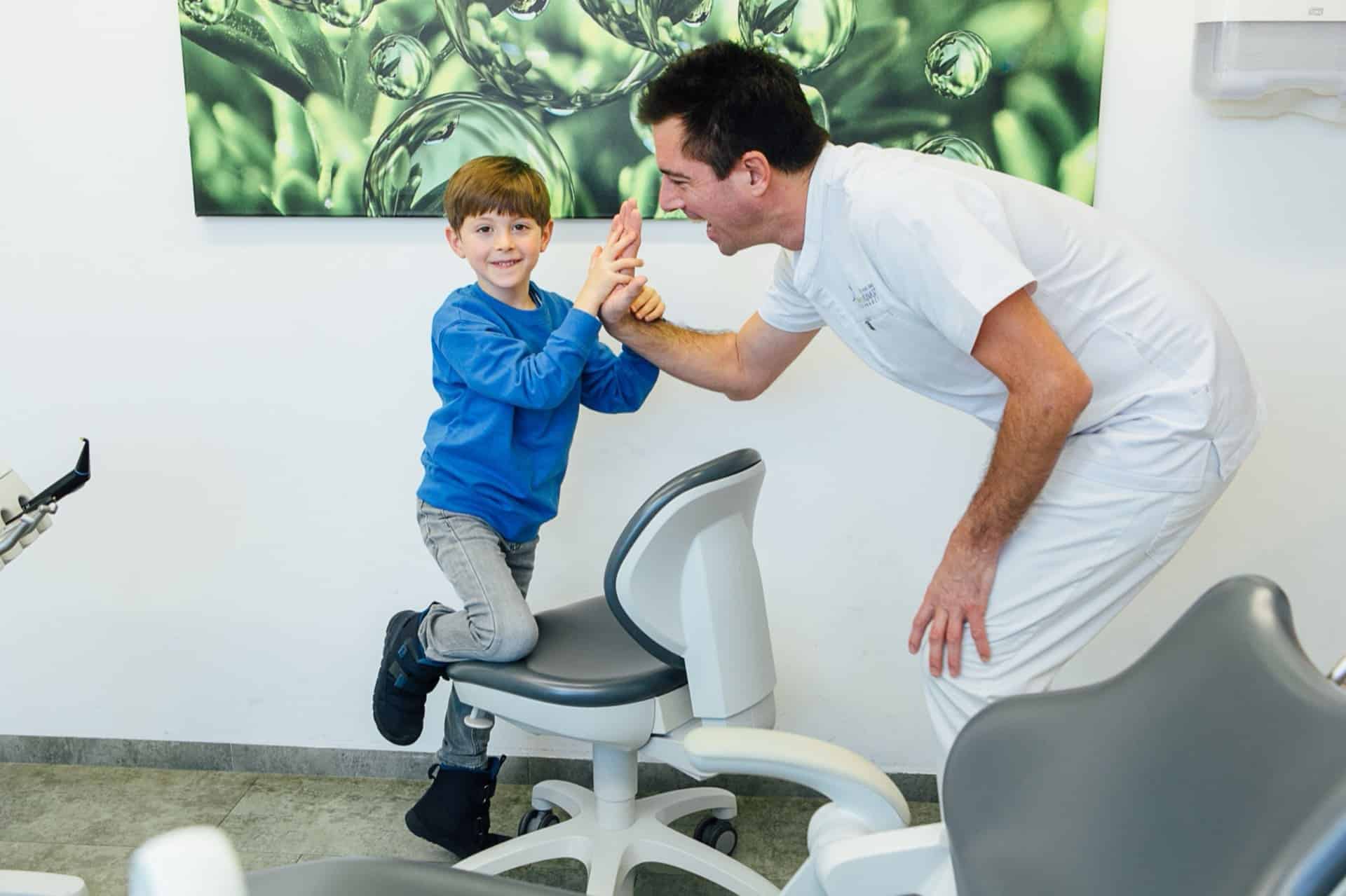 Dr. Bernd Kinast lacht mit einem Kind während einer Untersuchung in entspannter Atmosphäre.